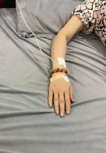 Ảnh truyền nước ở tay nữ với bàn tay nhẹ nhàng đặt trên giường